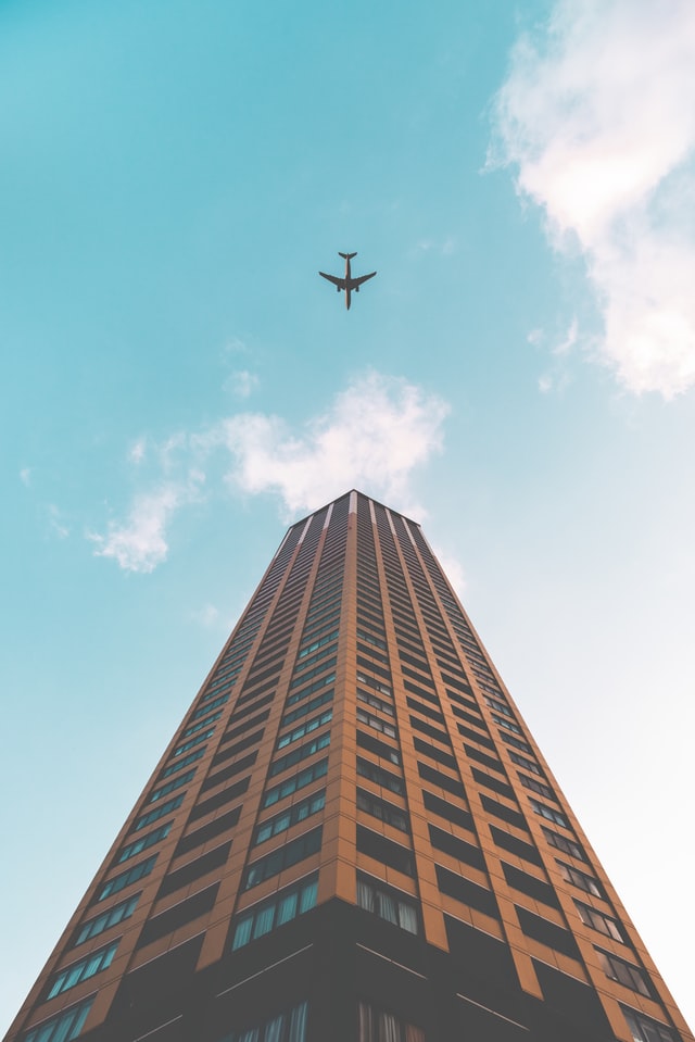Tall modern office building with plane flying over